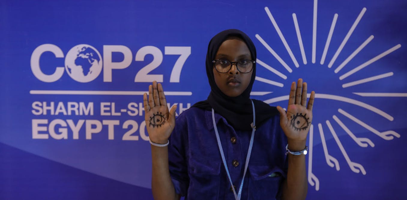 A female climate activist hold hands up in protest at the COP27 in Egypt