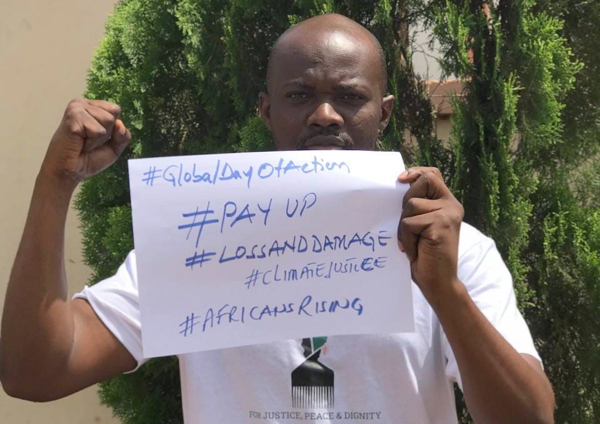 Africans Rising interim coordinator Hardi Yakubu holding a #LossAndDamage placard.