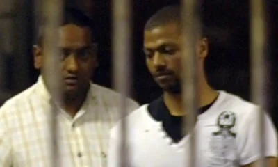 Policeman Shane Naidoo, left, leads Thabo Bester from holding cells in Durban.