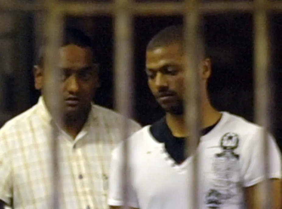 Policeman Shane Naidoo, left, leads Thabo Bester from holding cells in Durban.